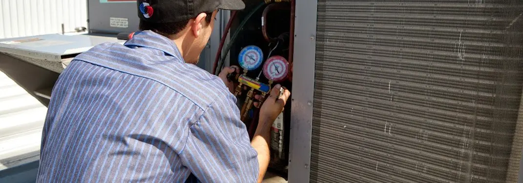 HVAC technician servicing a condenser unit in Ardmore